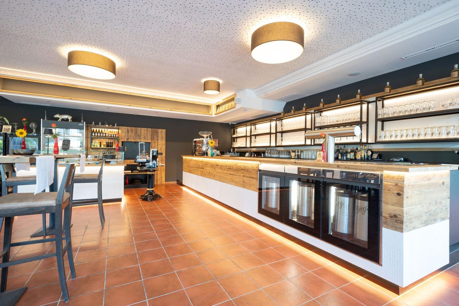 Dining room with an illuminated bar made of reclaimed wood and a terracotta floor